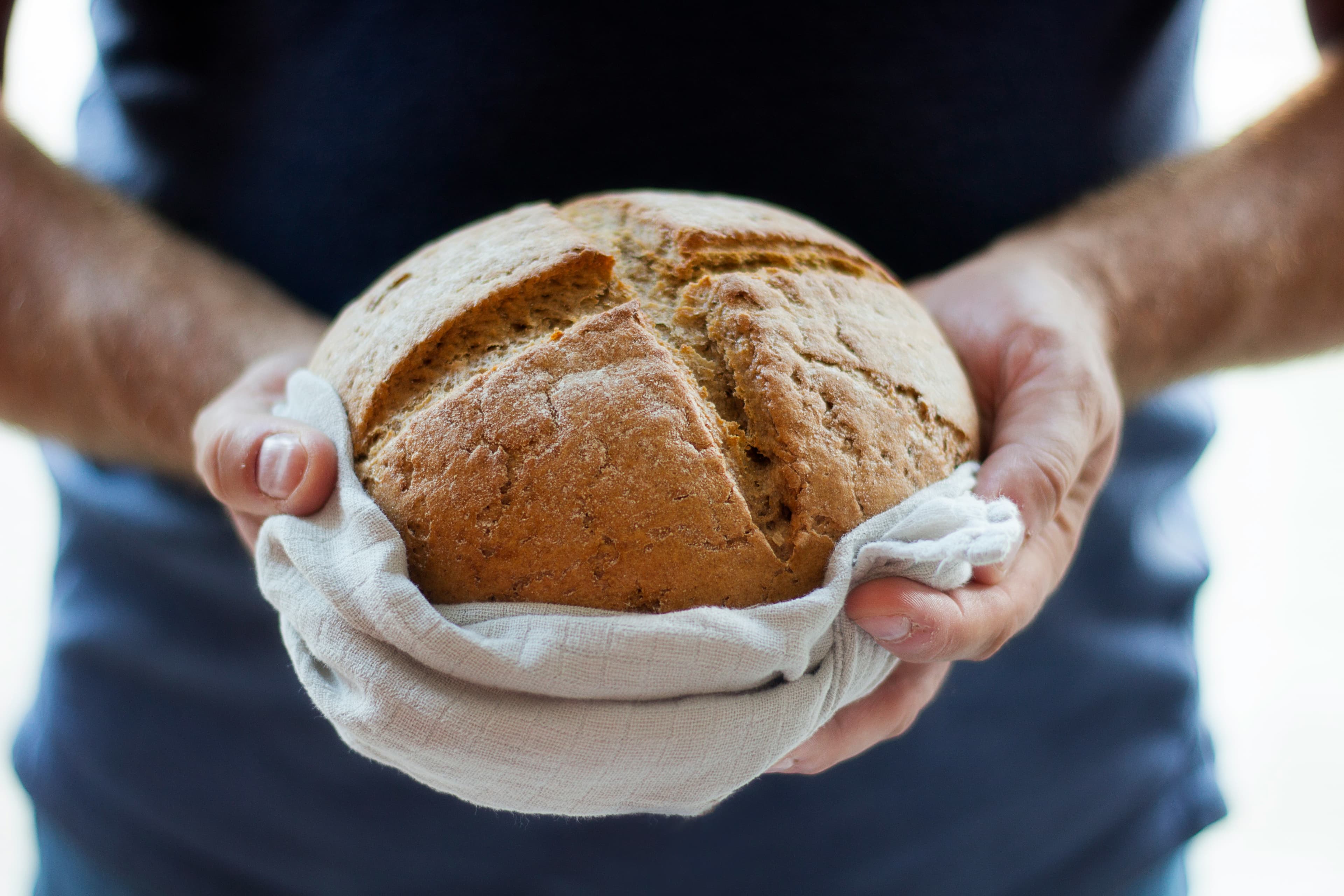 Freshly baked artisan bread held in a linen cloth